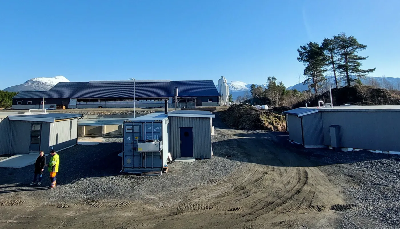 Anlegget til RIBI Bioenergi hvor Frass testes som biogassubstrat. Reaktorer til høyre og venstre. Teknikkonteiner med strøm- og varmeproduksjon i midten fremme. Melkekufjøs bak i bildet. (Foto: Ingvar Kvande)